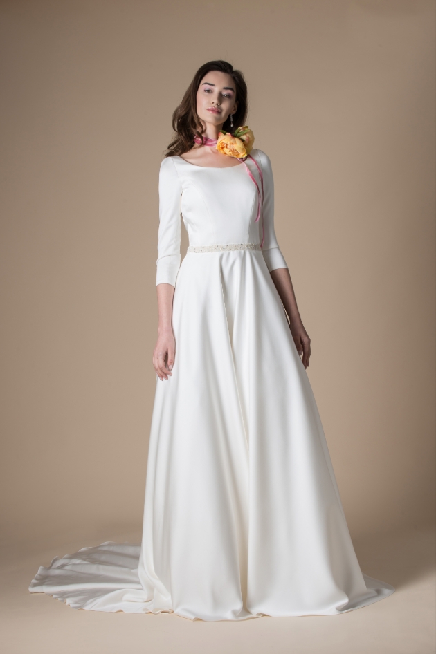 Model wears long white wedding dress and corsage necklace 