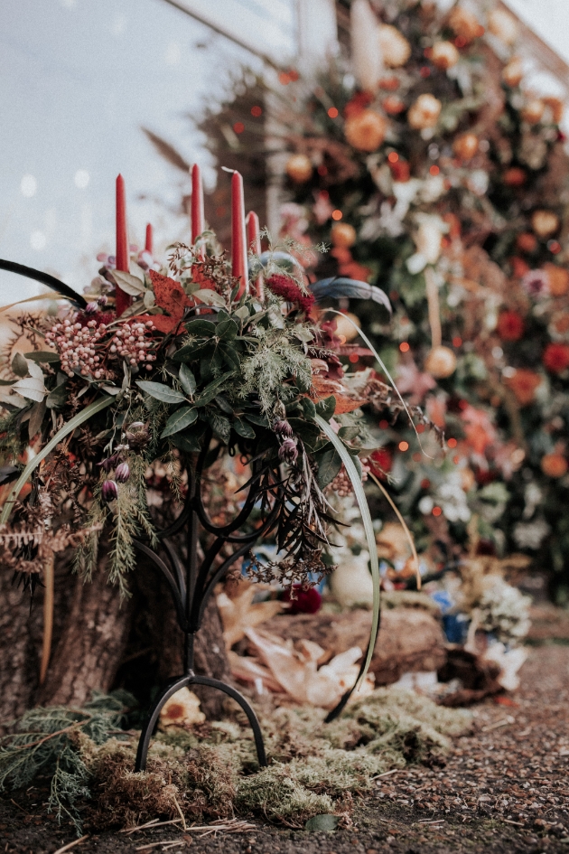 Autumnal flower display in candelabra with red candles