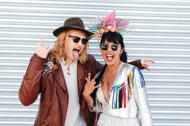 Festival wedding couple having fun making rock n roll sign