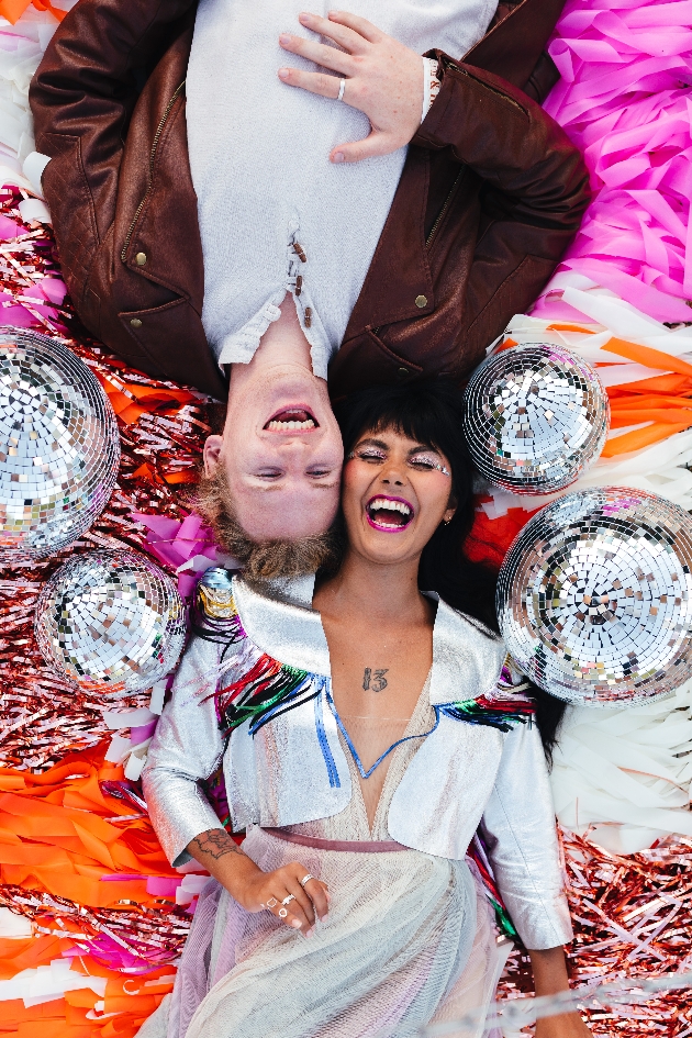 couple laying on the ground laughing surrounded by mirrorballs