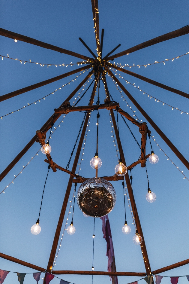 tipi structure at twilight decorated with large mirrorball and fairylights