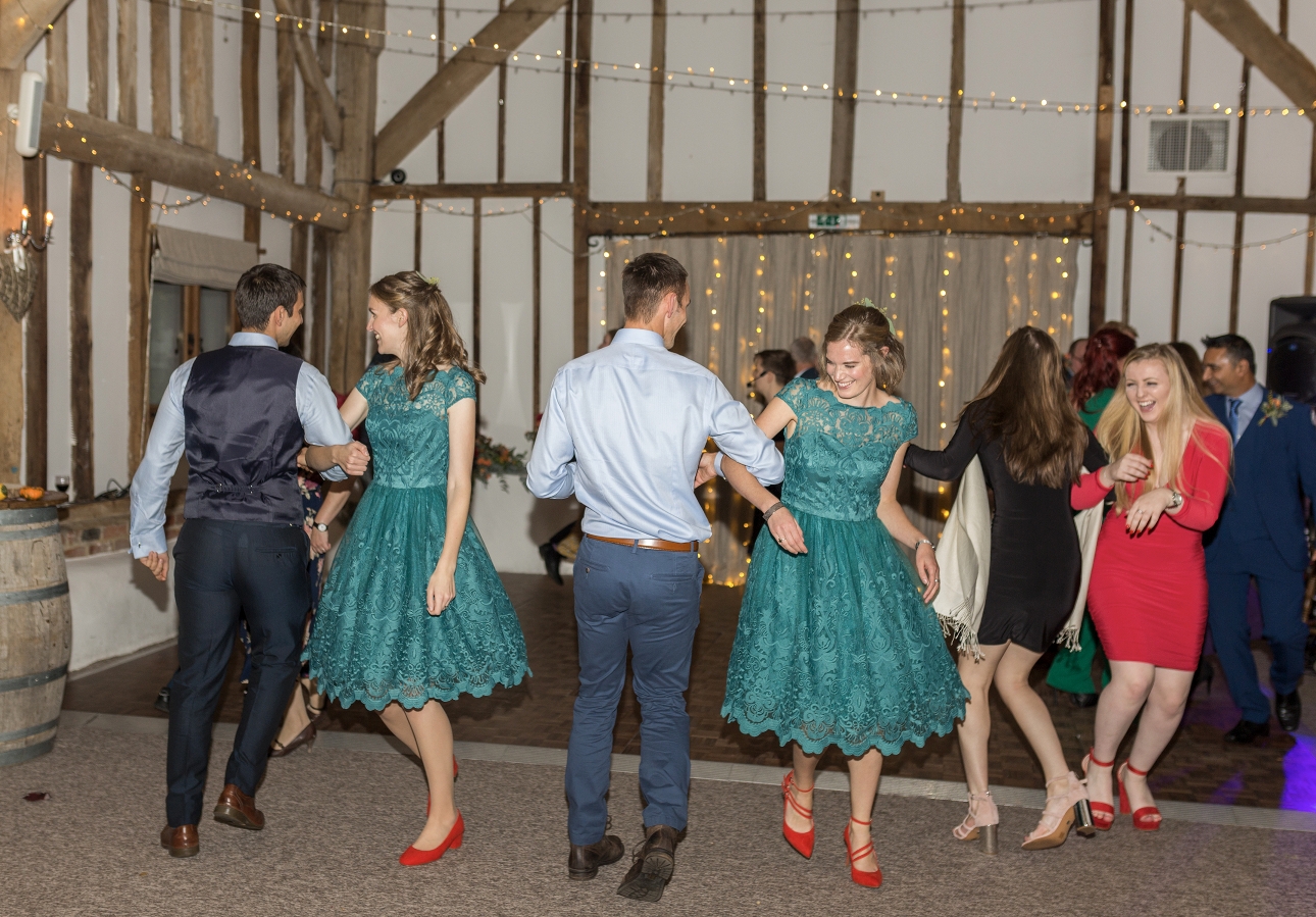 Bridesmaids dance in teal dresses and flame orange shoes