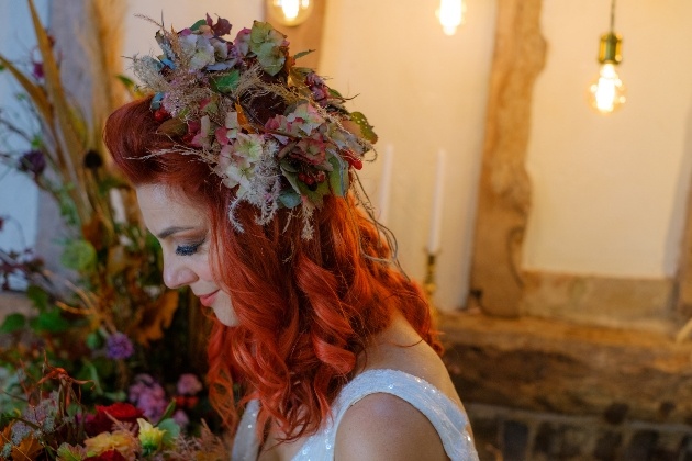 red head bride wearing rustic autumnal flower crown looking down at her bouquet