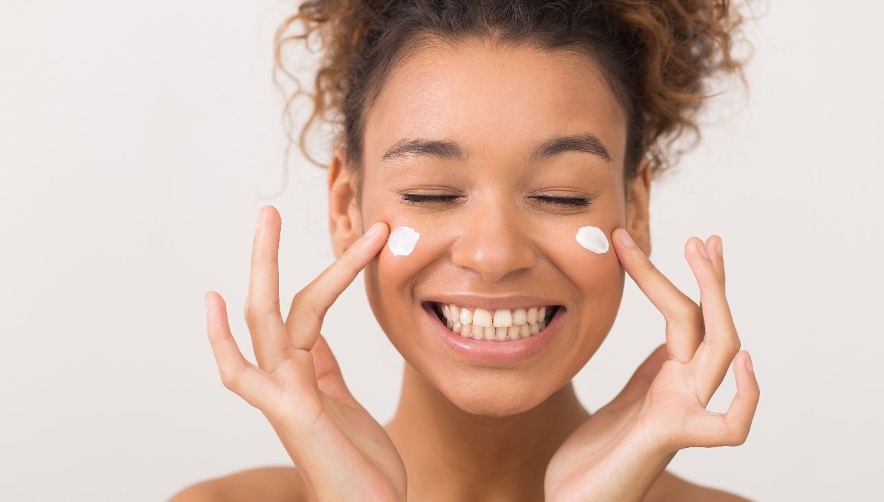 young lady dabbing moisturiser on each cheek