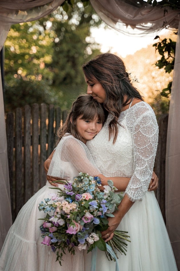 bride holding bouquet and flowergirl, hugging