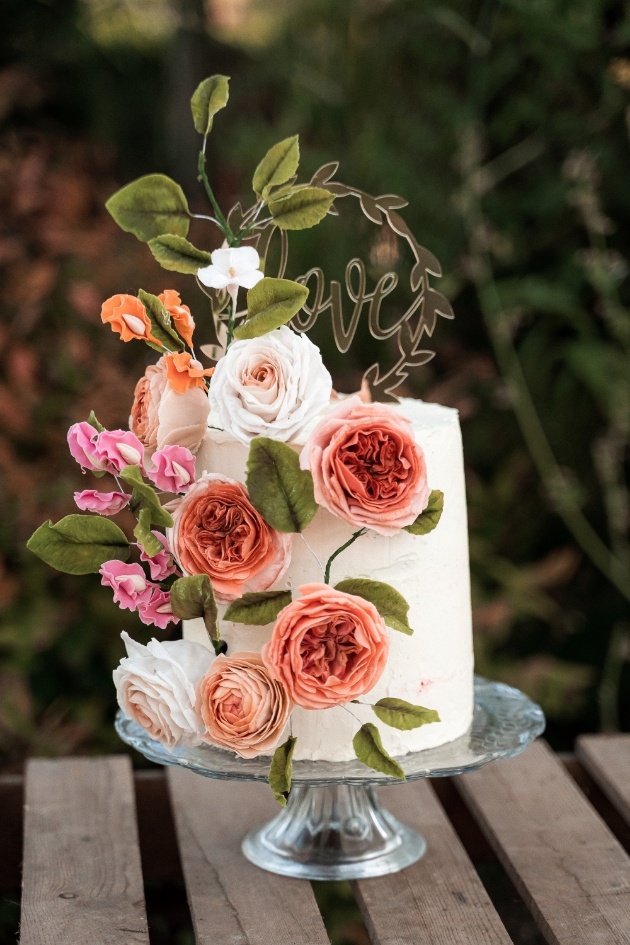 wedding cake with love cake topper, decorated with pink florals
