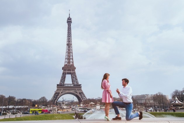 couple in front of Eiffel tower in middle of proposal he is down on one knee
