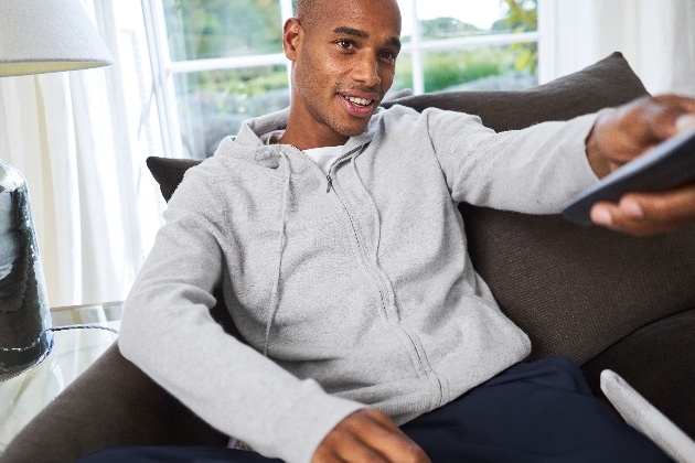 man in loungewear on sofa holding remote control 