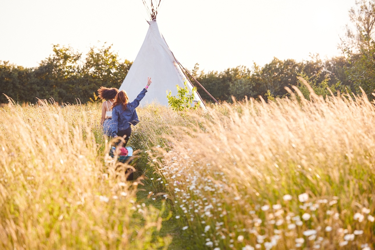 two ladies running through field towards teepee