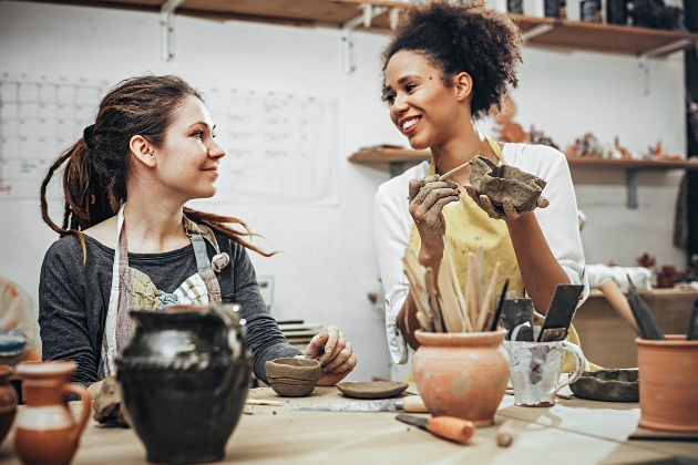 two women at a pottery class painting