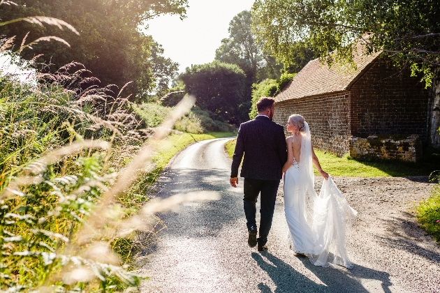 Couple walking down a country lane hand in hand away from us