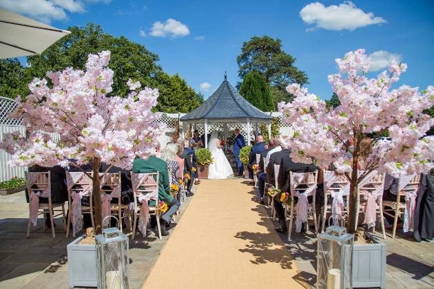 Gazebo wedding with aisle lined with pink blossom trees