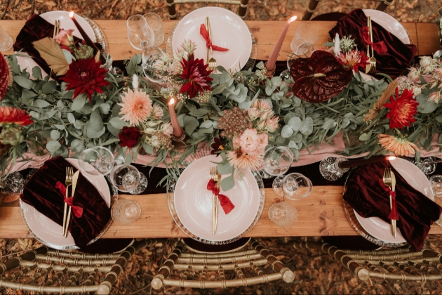 overhead view of wedding table set up with blush and burgundy florals and burgundy velvet napkins pink candles