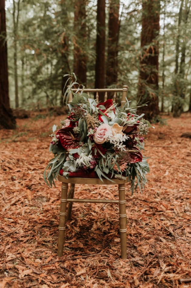 bridal bouquet sitting on a chair in the woods hues of blush pink and burgundy