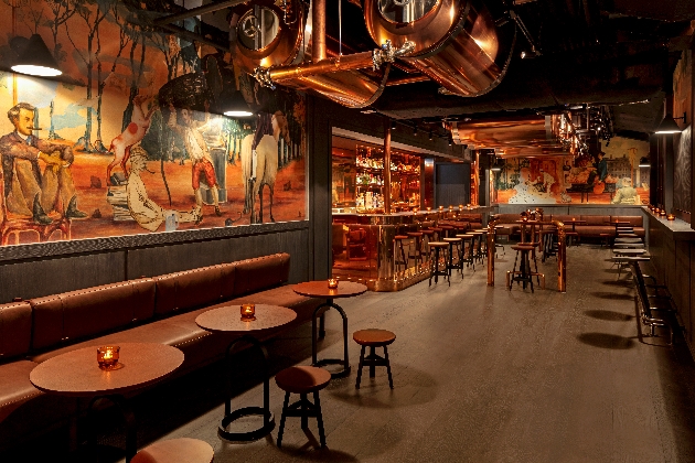 bar at night with low lighting, artwork on the walls and copper finishing touches