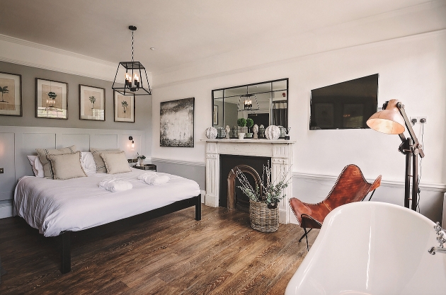 bedroom with neutral colour palette, dark wood floor and roll top bath