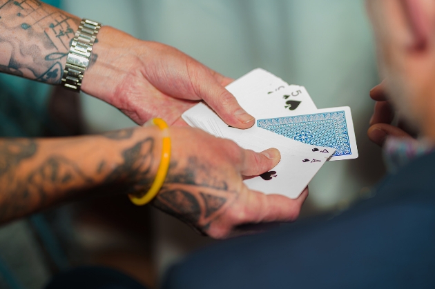 Tattooed magicians hands perform a card trick