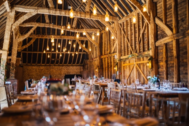 interior of brick and beamed barn with wooden tables laid out 