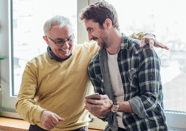 two men laughing when looking at a phone