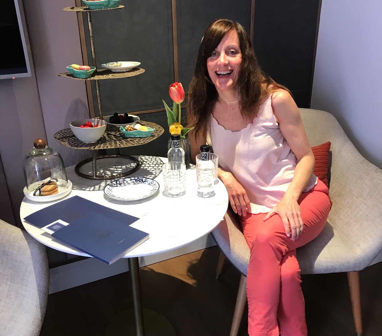 editor claire dressed in pink at a table with afternoon tea on