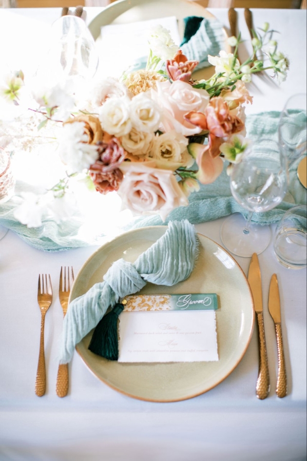 Wedding table set up with pale blue linen, acrylic place name and pink floral centrepieces