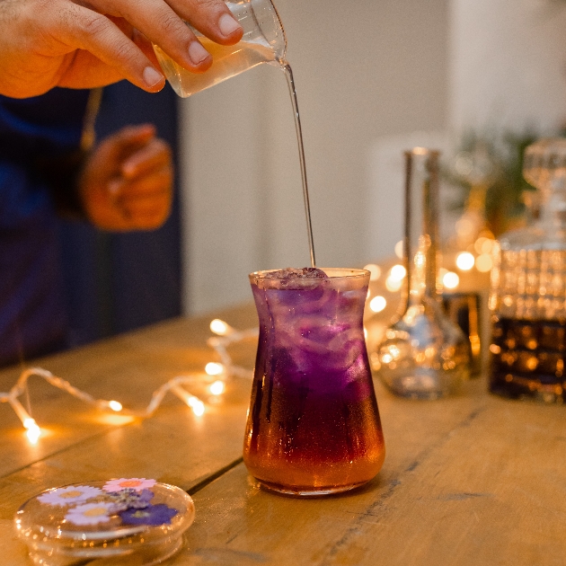 hand pouring fluid in to a container of purple fluid