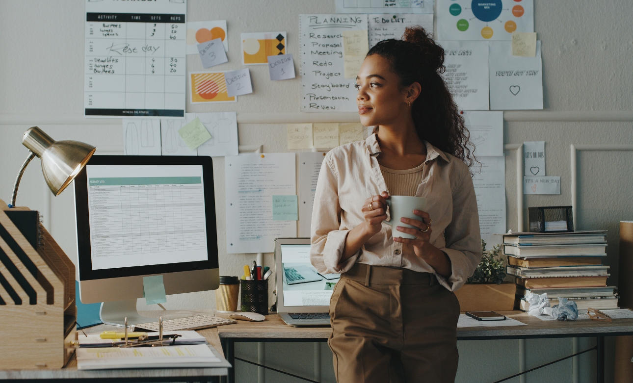 woman at work at her desk holding a mug of coffee