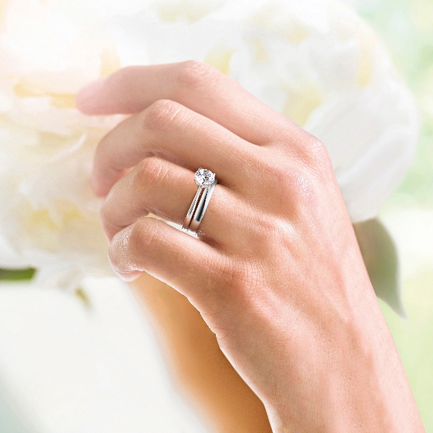 close up of hand wearing engagement and wedding ring