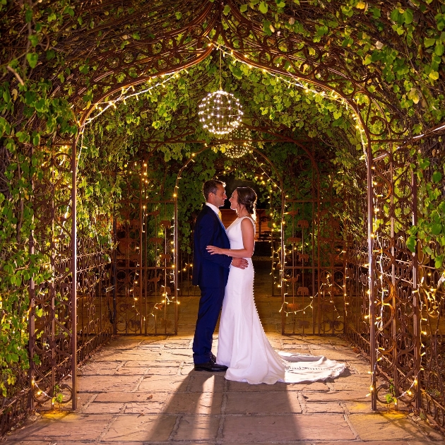 Couple standing underneath an arch covered in lights
