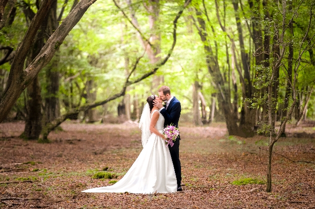 Bride and groom kissing in the middle of the woods