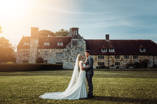 A bride and groom embracing outside Michelham Priory House & Gardens