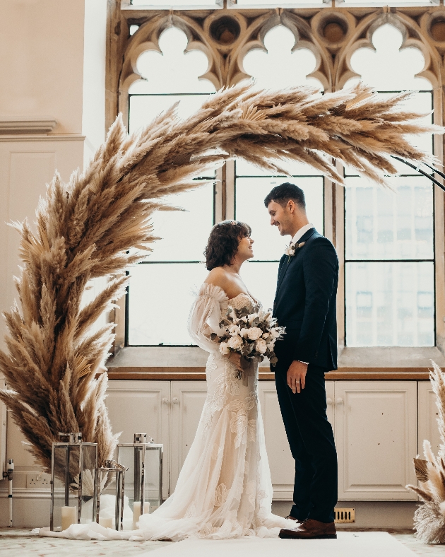 Bride and groom beneath pampas ceremony arch