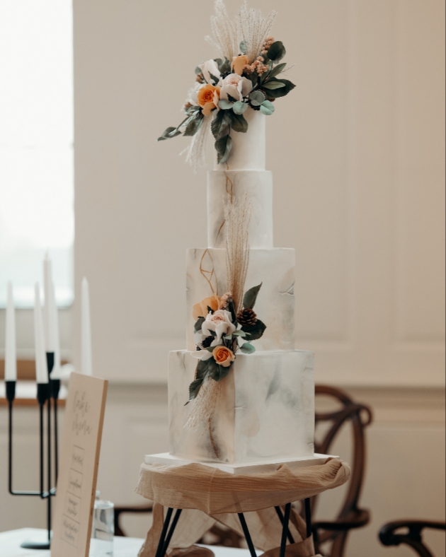 wedding cake with four tiers and peach and white sugar flower decoration