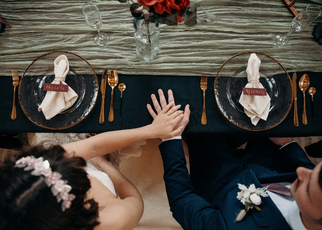 wedding table set up with clear plates, gold cutlery, napkins and place names