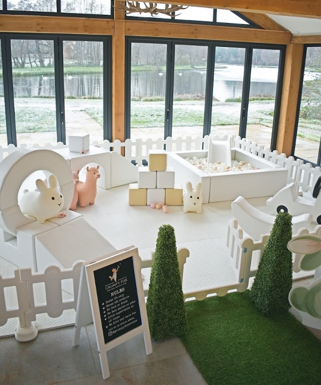 white soft play set up with fake green grass and garden gate