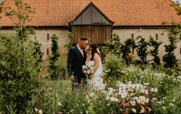 Bride and groom kiss outside wedding barn at Field Place Manor & Barns in Worthing