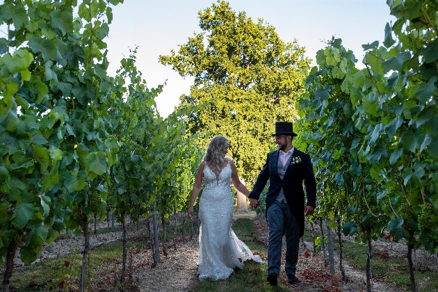 Bride and groom holding hands among the vineyards at Mannings Heath