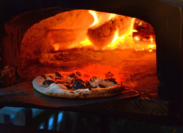 A pizza going into a wood fired oven