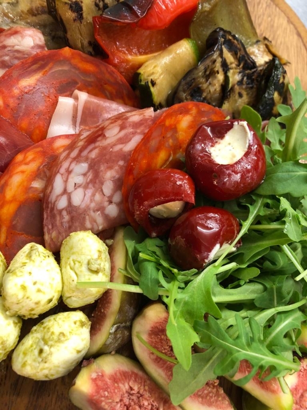 Close up of a grazing platter with pesto mozzarella salami rocket aubergines and more
