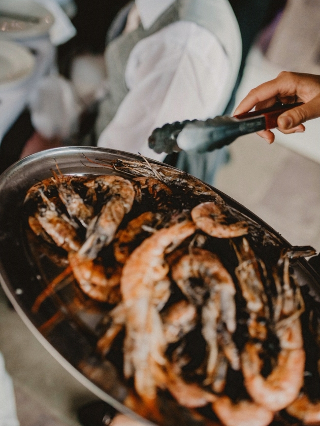 barbecued prawns being served with tongs
