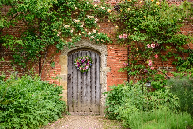 Door to the walled garden at Cowdray Estate surrounded by flowers