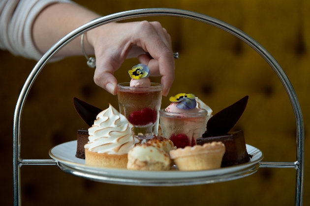 Hand picking up a delicate jelly pot from afternoon tea stand Grand Brighton