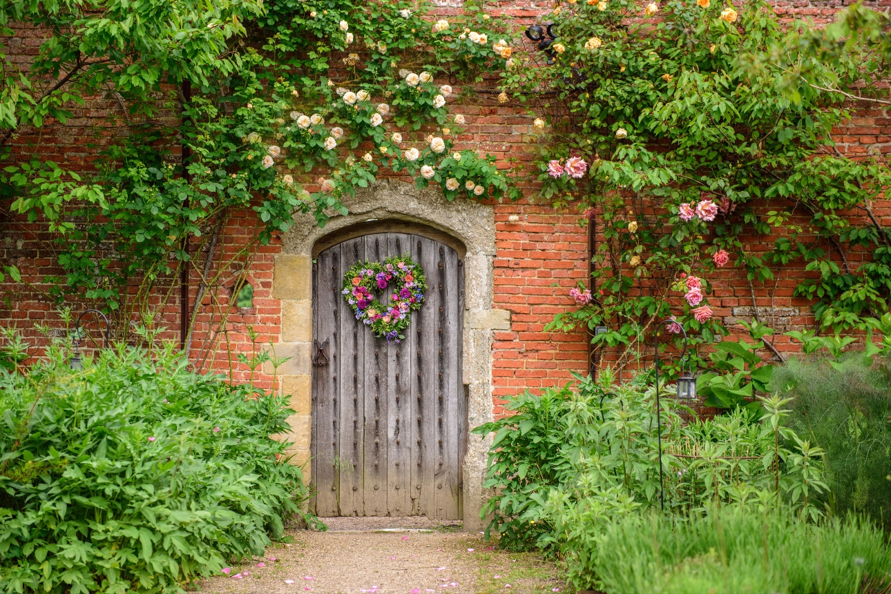 Wooden door entrance to Walled Garden at Cowdray surrounded by flowers
