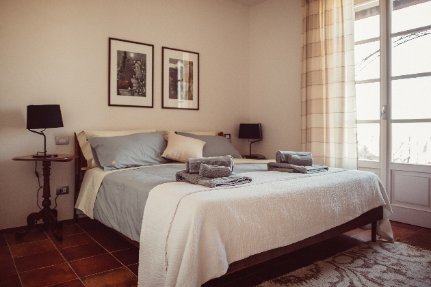 A bed next to a window with two pictures above the bed