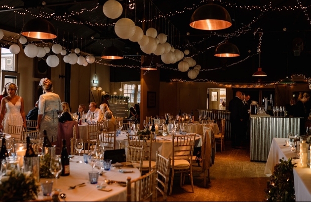 room with wedding reception happening globe lights and fairylights hanging from ceiling