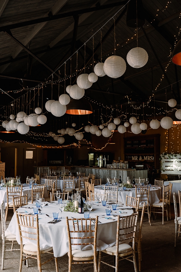 laterns hanging from ceiling from barn style room at wedding reception