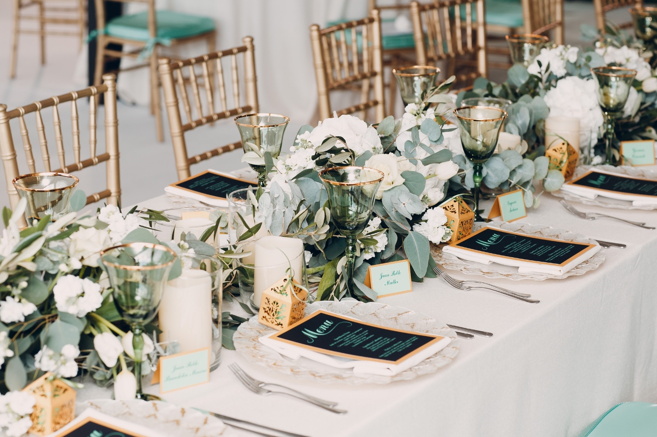 wedding table at reception laid out with glasses, plates, flowers etc