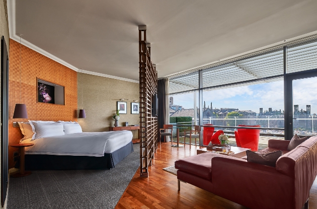 A bedroom with large windows that overlook Edinburgh