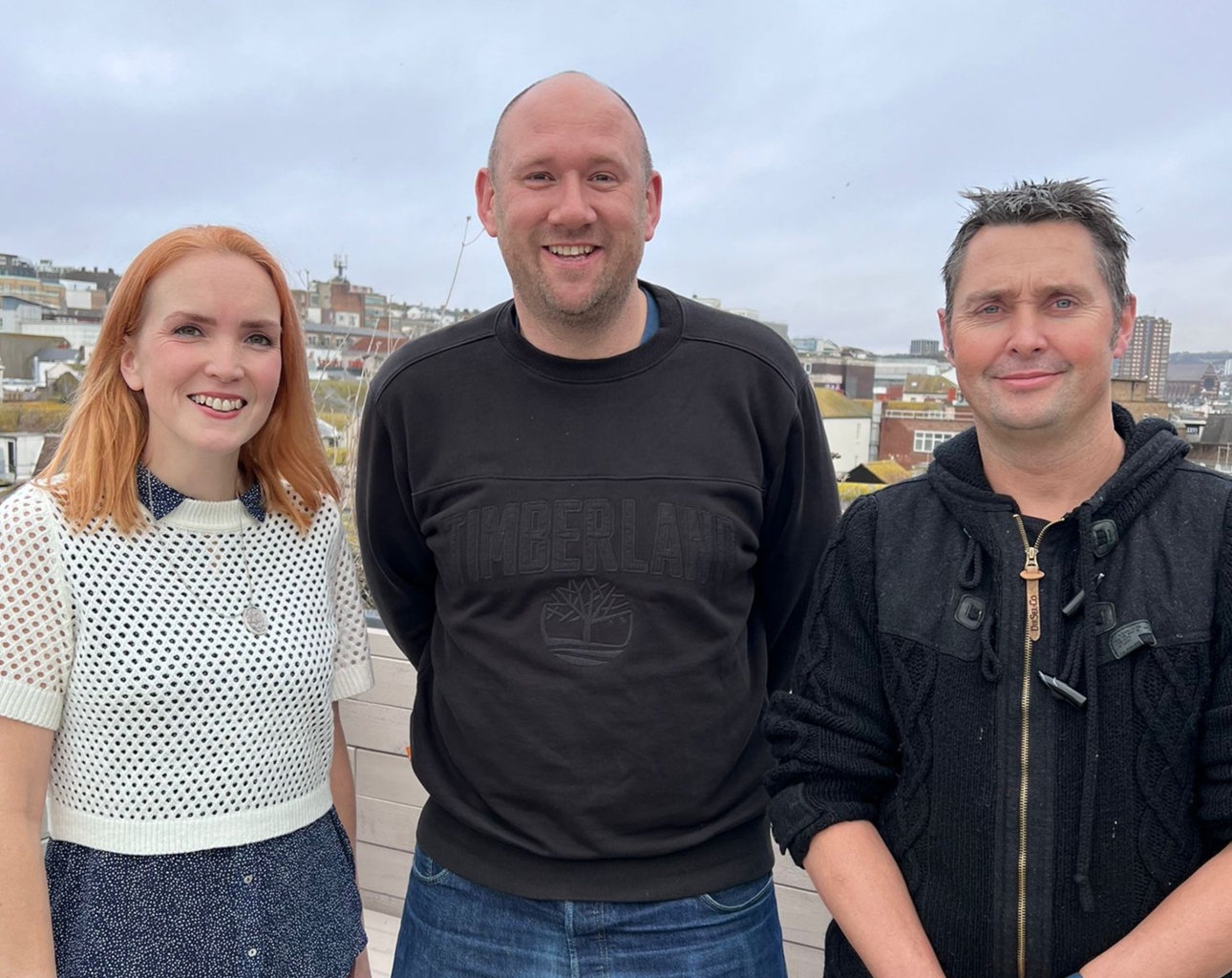 three people two men and a woman standing outside