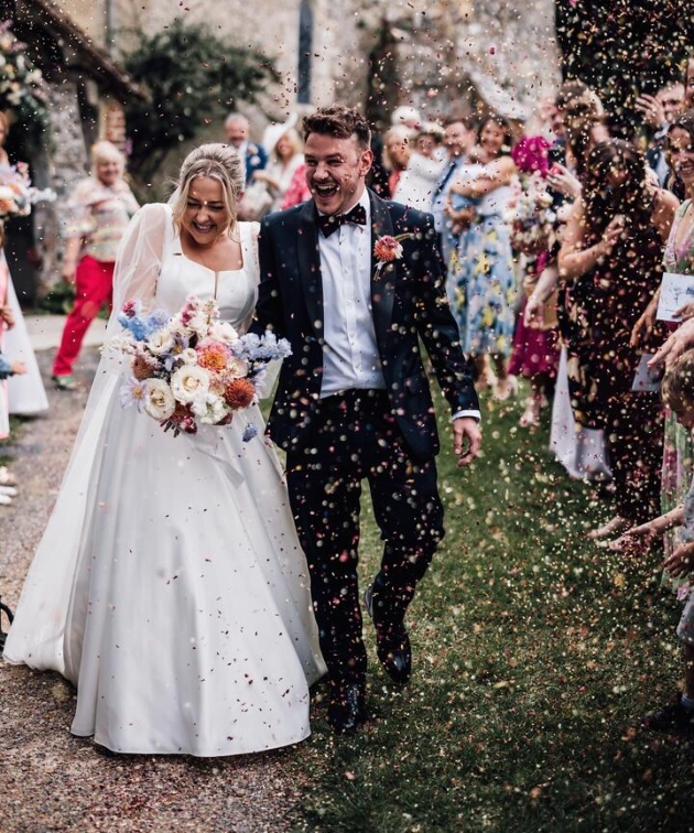 Bridge and groom leaving ceremony through confettin throw